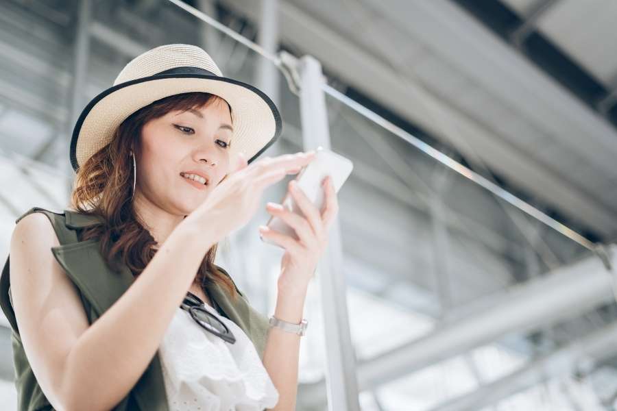 Une voyageuse consulte son application mobile pour vérifier ses données bancaires en voyage dans une gare.