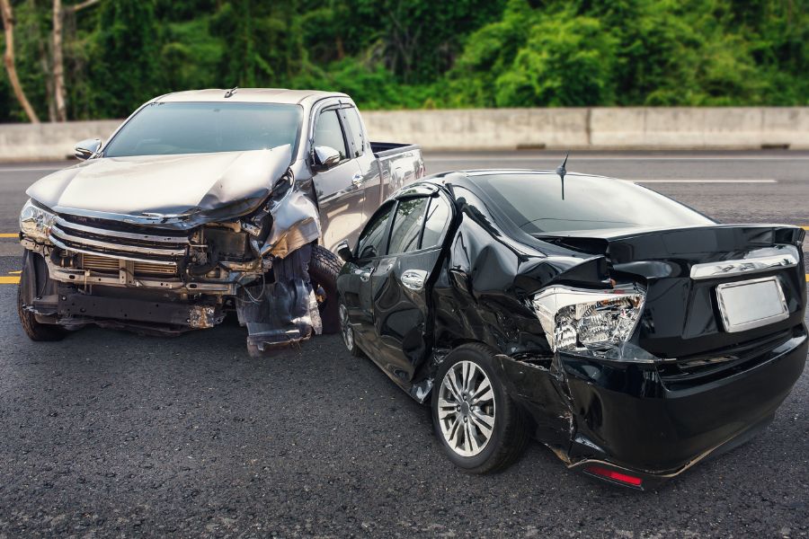 Une camionnette grise et une voiture noire endommagées après une collision sur la route, illustrant un accident de la route.